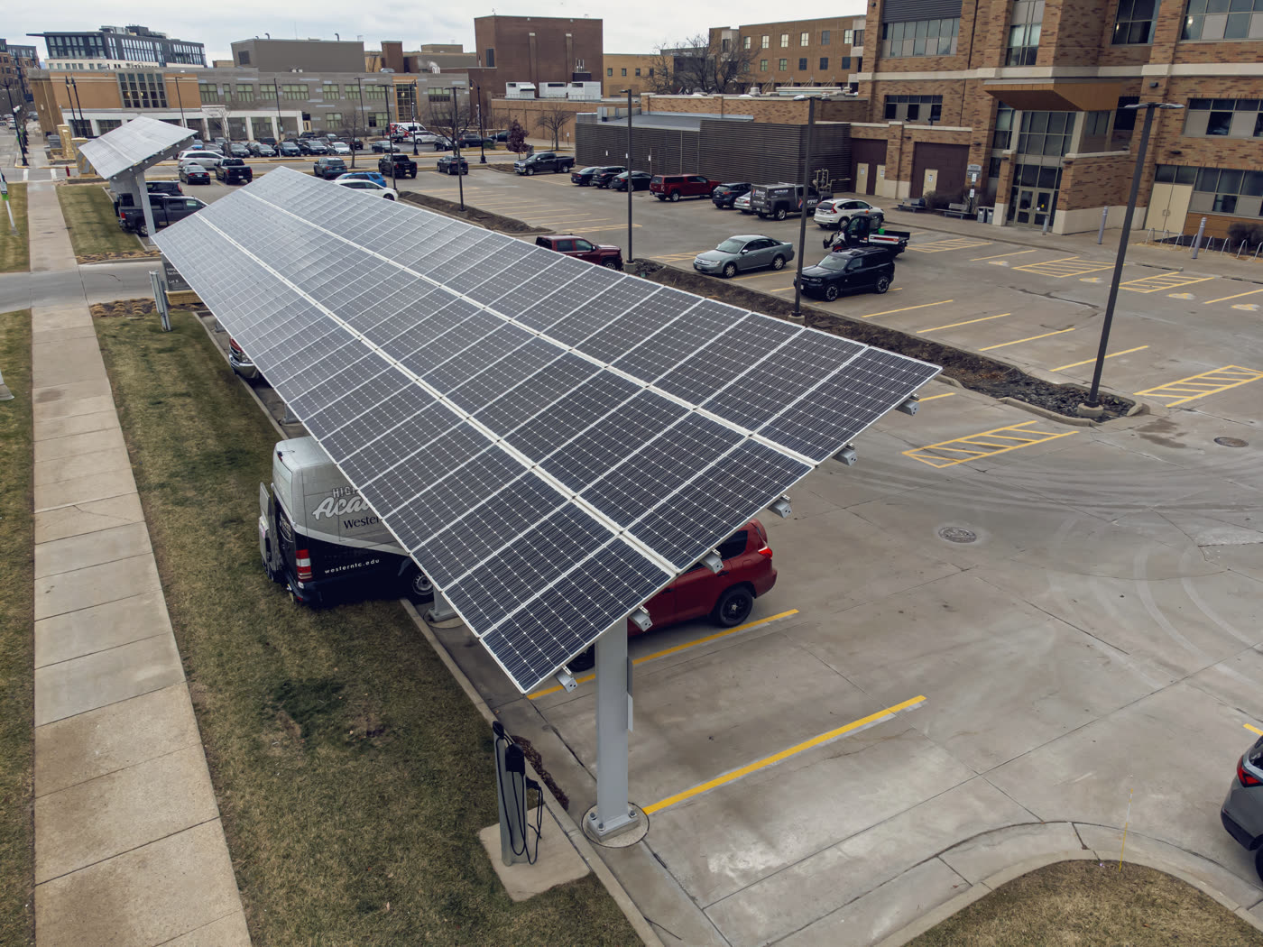 Ombrière solaire abritant des véhicules sur un parking, avec borne de recharge