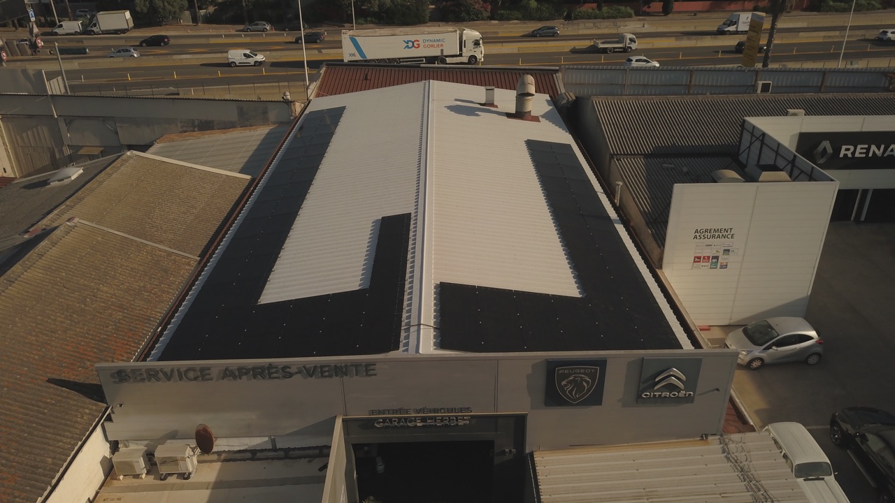 Toiture d'un bâtiment professionnel (concession automobile) couverte de panneaux solaires, vue aérienne